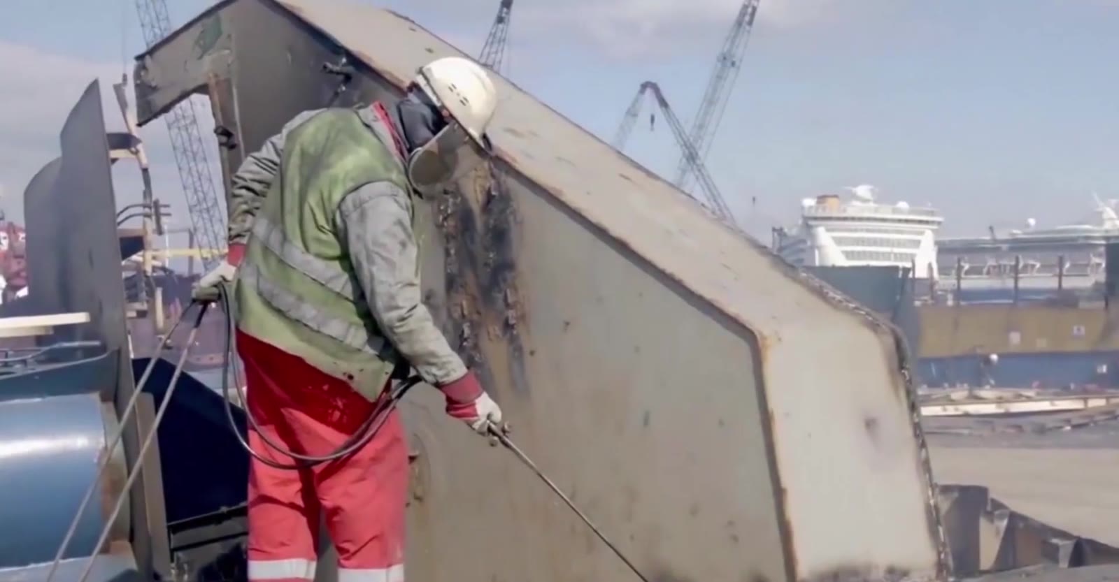 Two workers in safety gear cutting steel with a torch, sparks flying