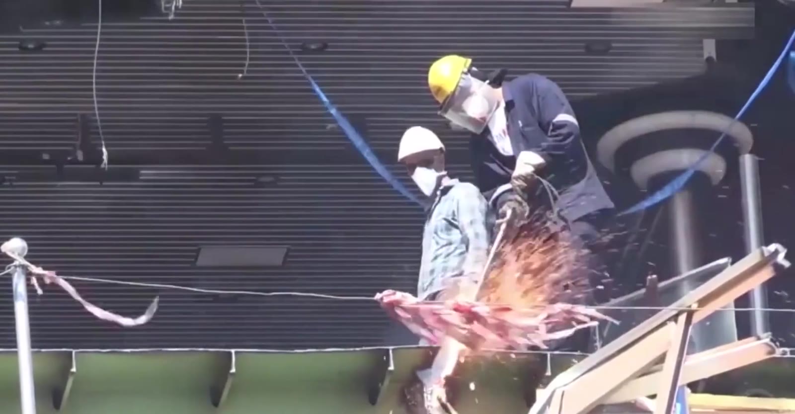Workers on a scaffold walkway between hull sections at the yard